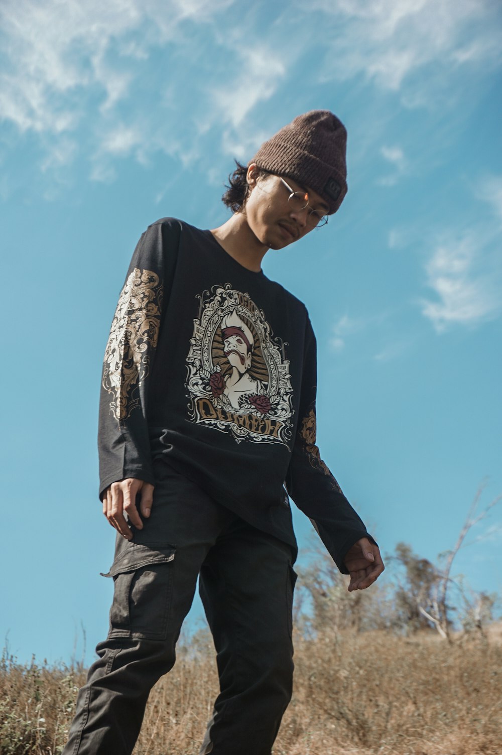 man in black and white long sleeve shirt and black knit cap standing under blue sky