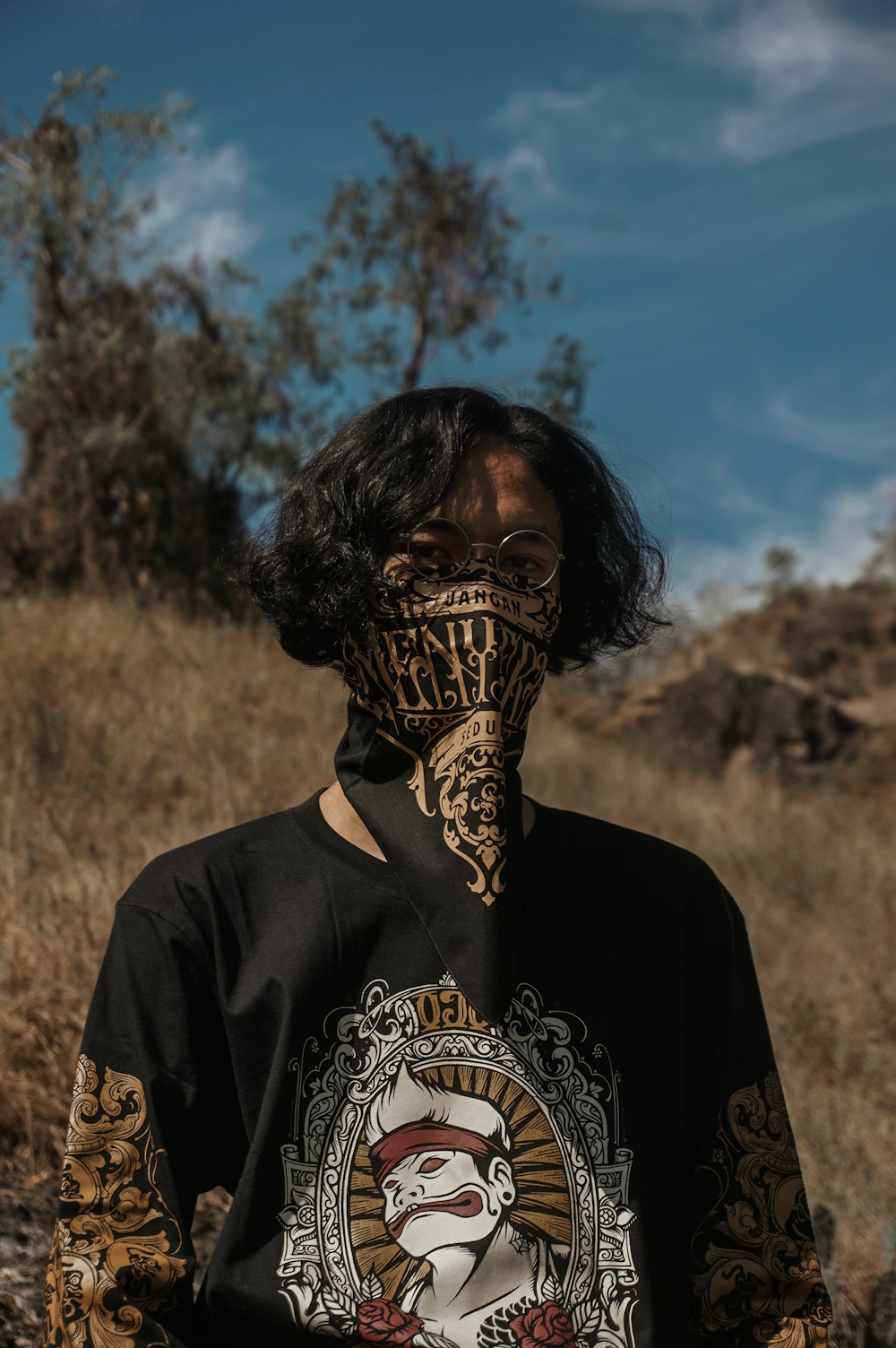 man in black and gold crew neck t-shirt standing on brown grass field during daytime