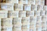 Rows of cylindrical wooden boxes are stacked, each labeled with printed text and graphics. The boxes appear to contain cheese, indicated by the words and imagery on the packaging.