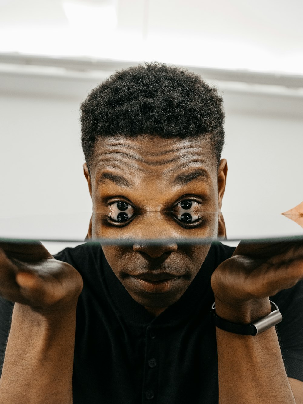 man in black crew neck shirt holding brown wooden frame