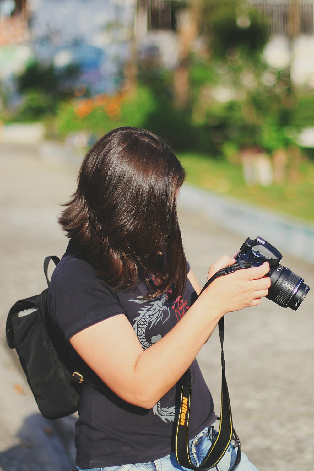 woman in black tank top holding black dslr camera