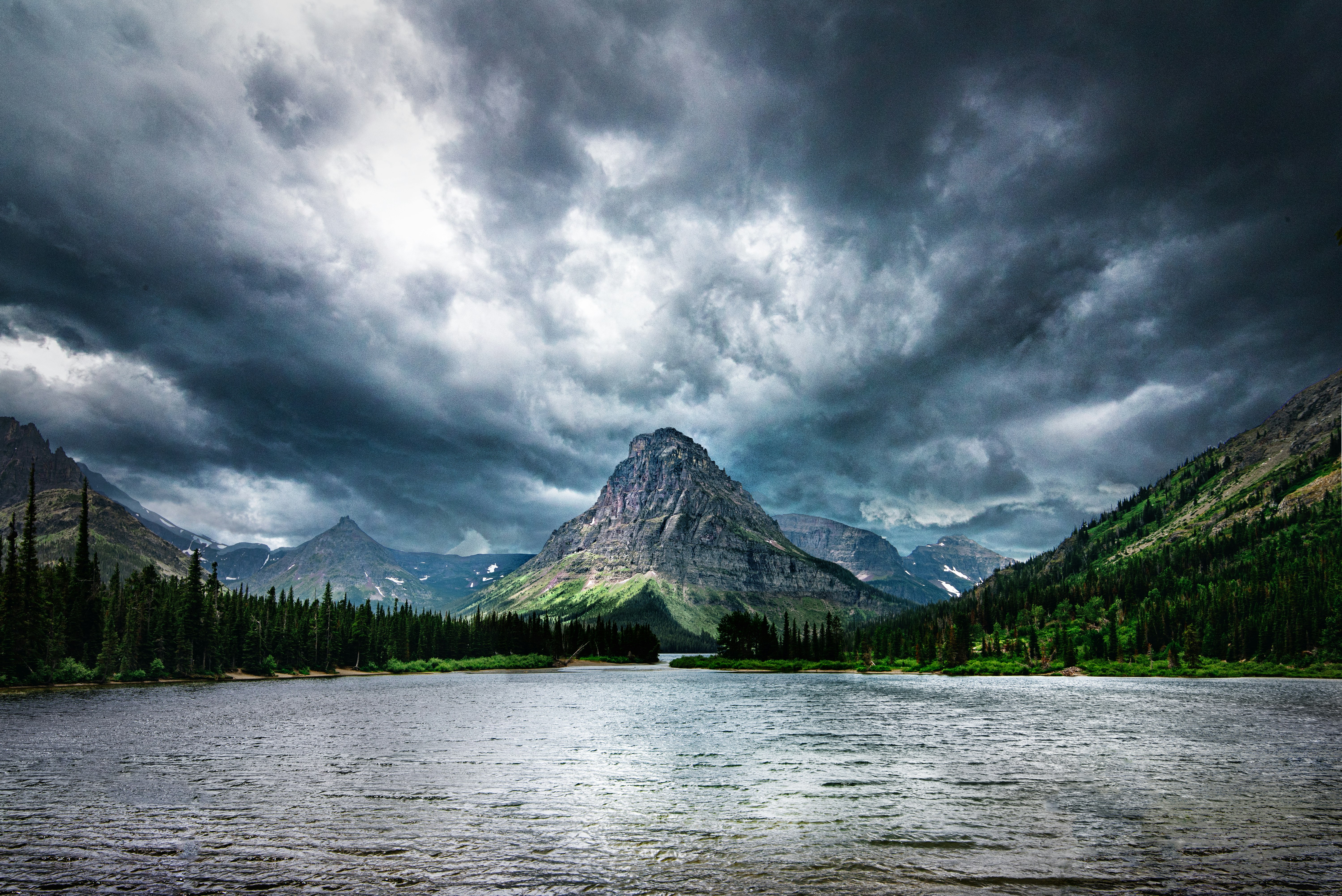 green trees near body of water under cloudy sky during daytime