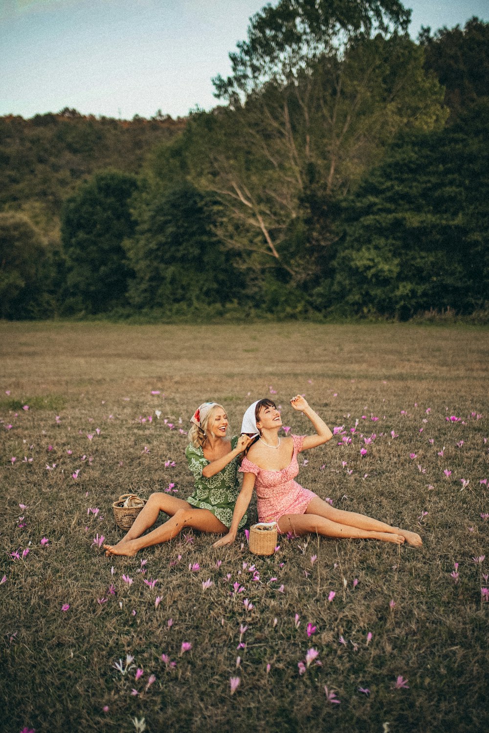 낮 동안 보라색 꽃밭에 앉아 분홍색 드레스를 입은 2명의 여성