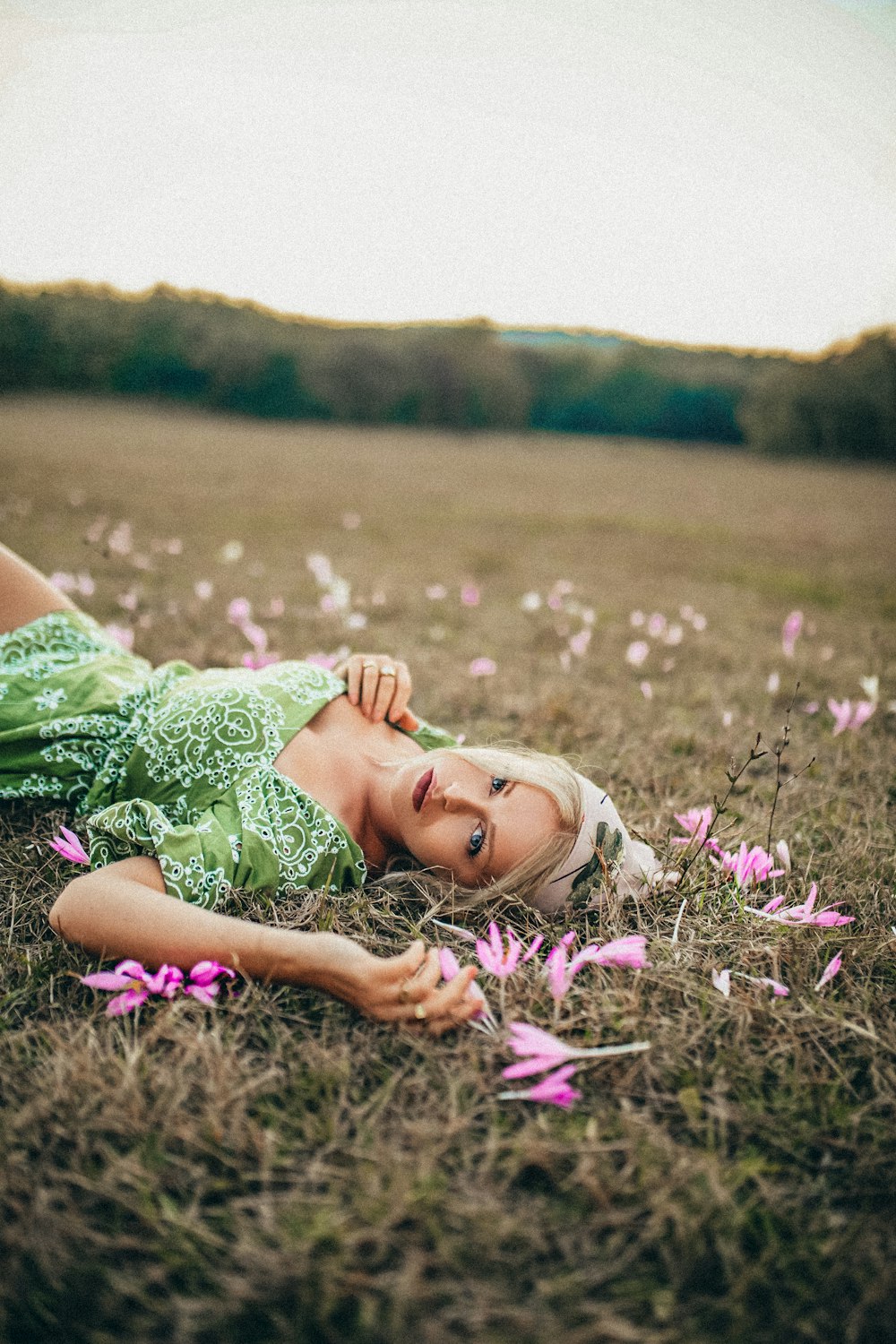 woman in green dress lying on purple flower field during daytime