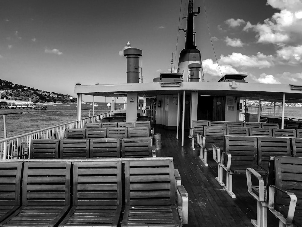 grayscale photo of wooden benches near body of water