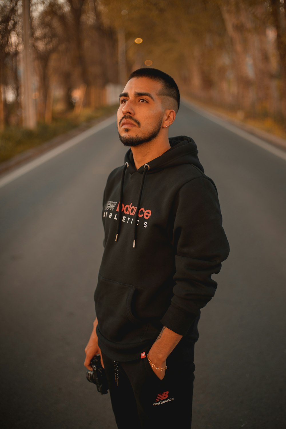 man in black hoodie standing on road during daytime