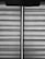 Horizontal blinds with a fabric texture are partially drawn, allowing a vertical sliver of light to pass through. A pull cord hangs from the upper portion of the blinds.