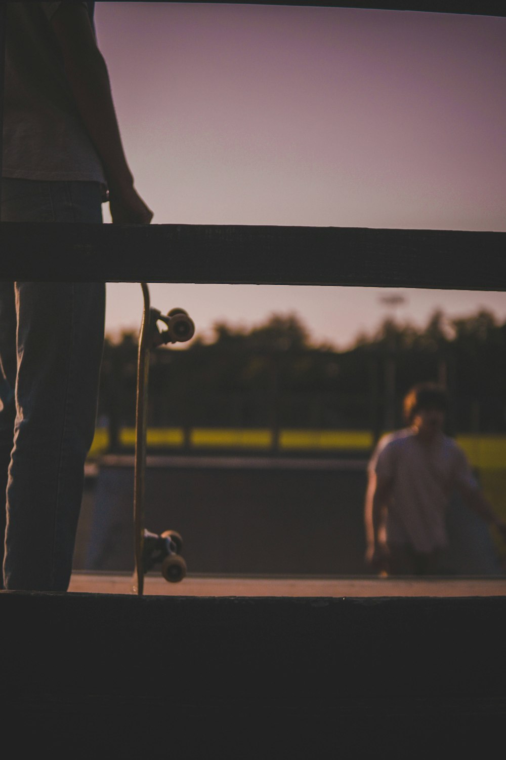 man in black t-shirt and pants standing on brown wooden fence during daytime