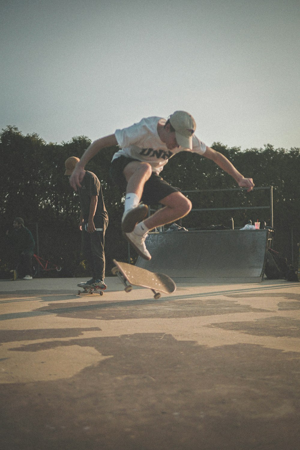 man in white t-shirt and blue denim shorts doing skateboard stunts during daytime