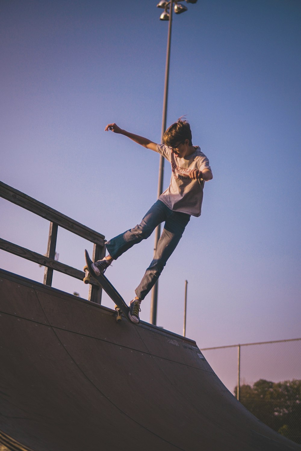 woman in white jacket and blue denim jeans jumping on black metal railings during daytime