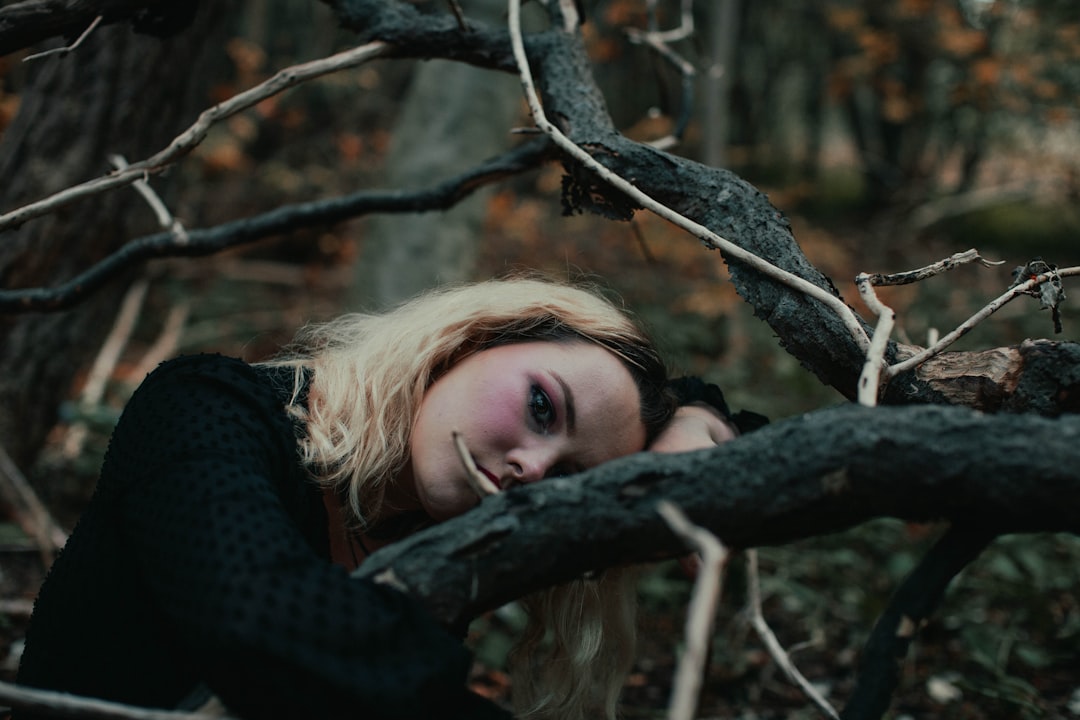 woman in black long sleeved shirt leaning on brown tree