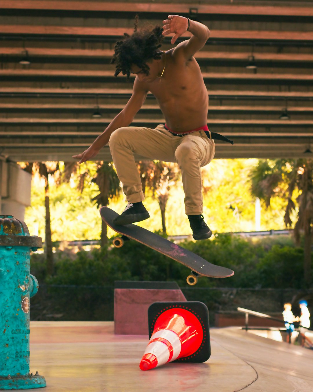 man in brown pants and white sneakers jumping on blue metal bar during daytime