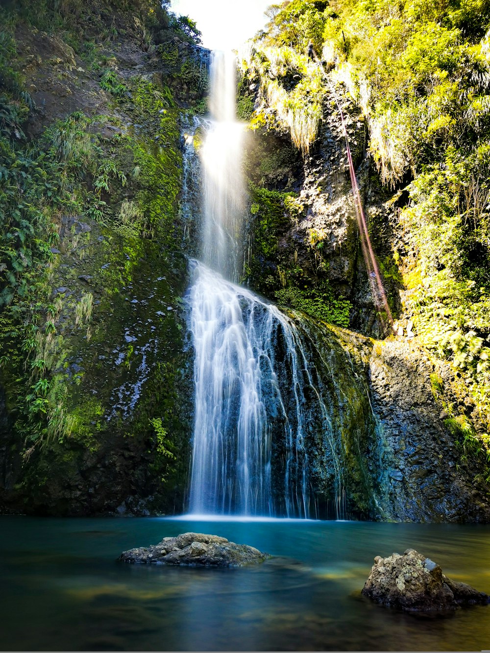 a waterfall with a blue pool in the middle of it