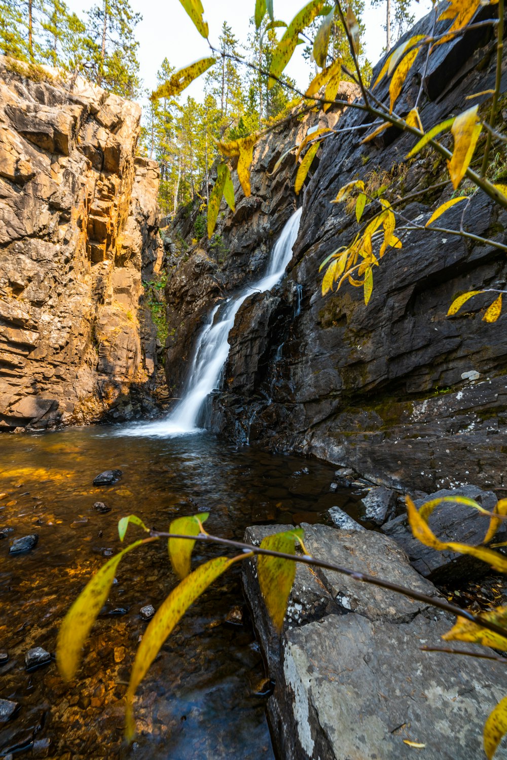 water falls in the middle of brown rocky mountain