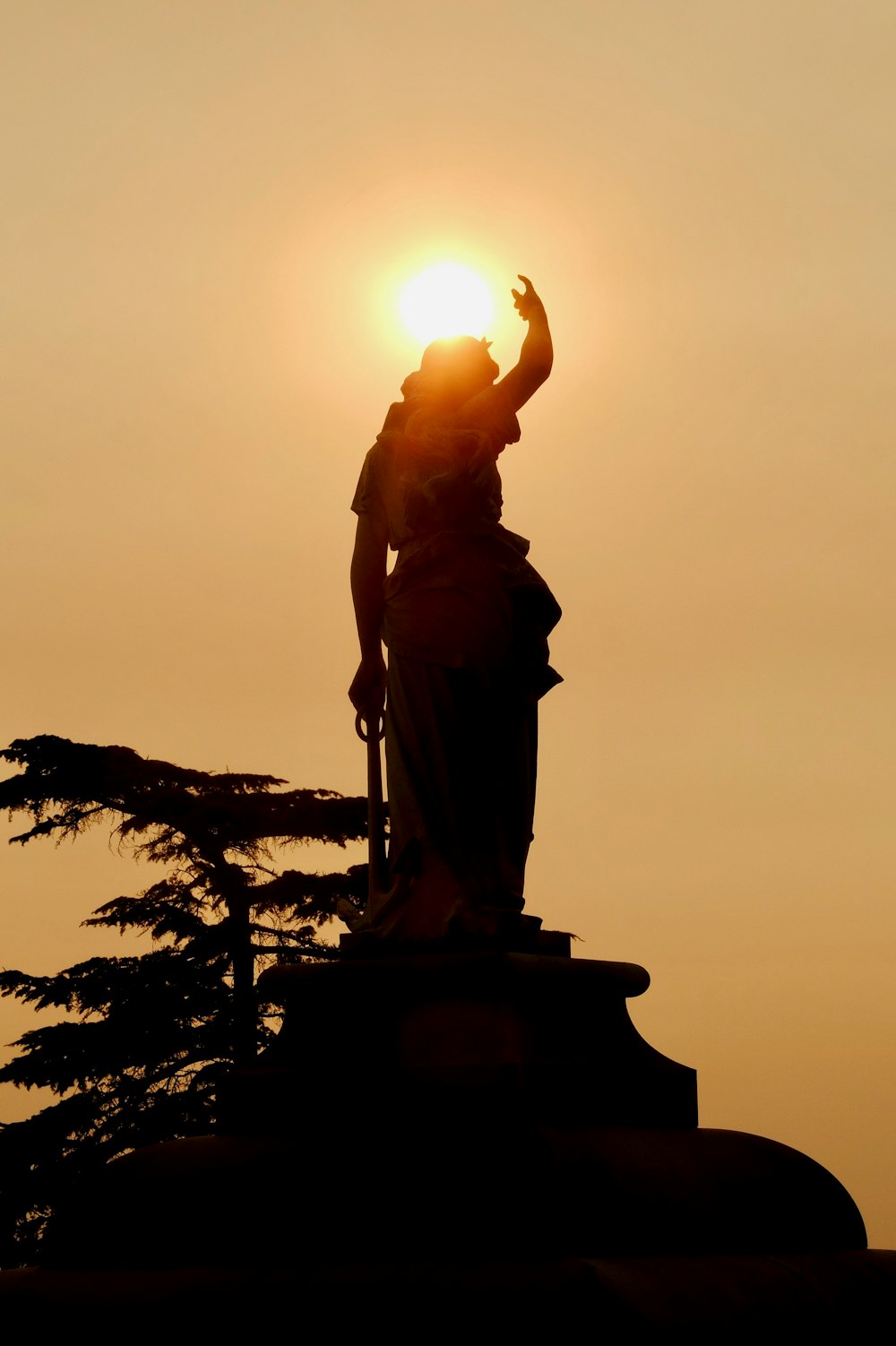 statue of man holding book during sunset