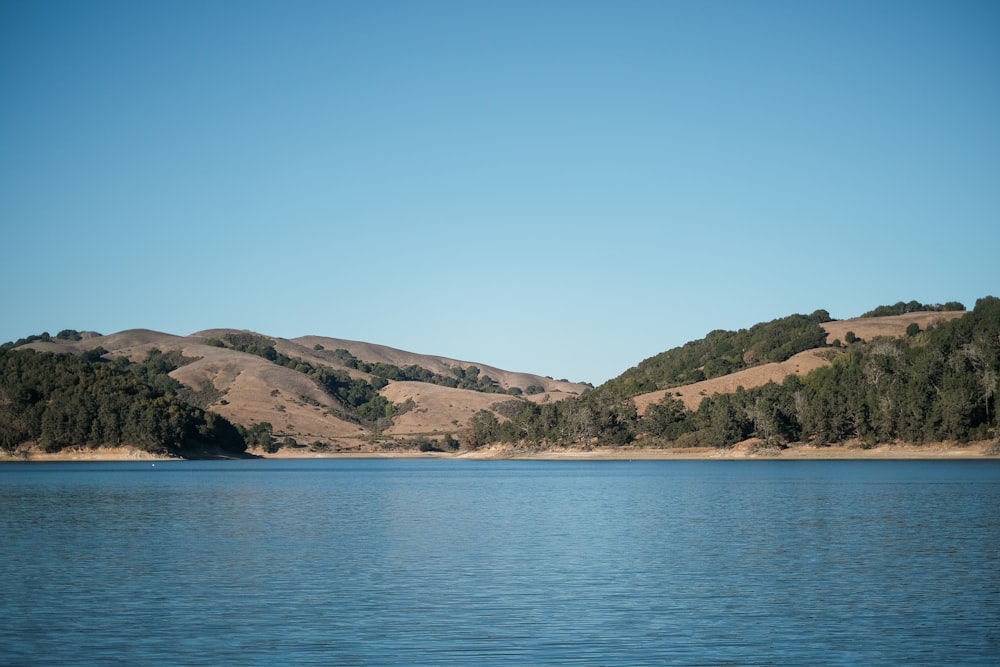 green and brown mountains beside body of water during daytime