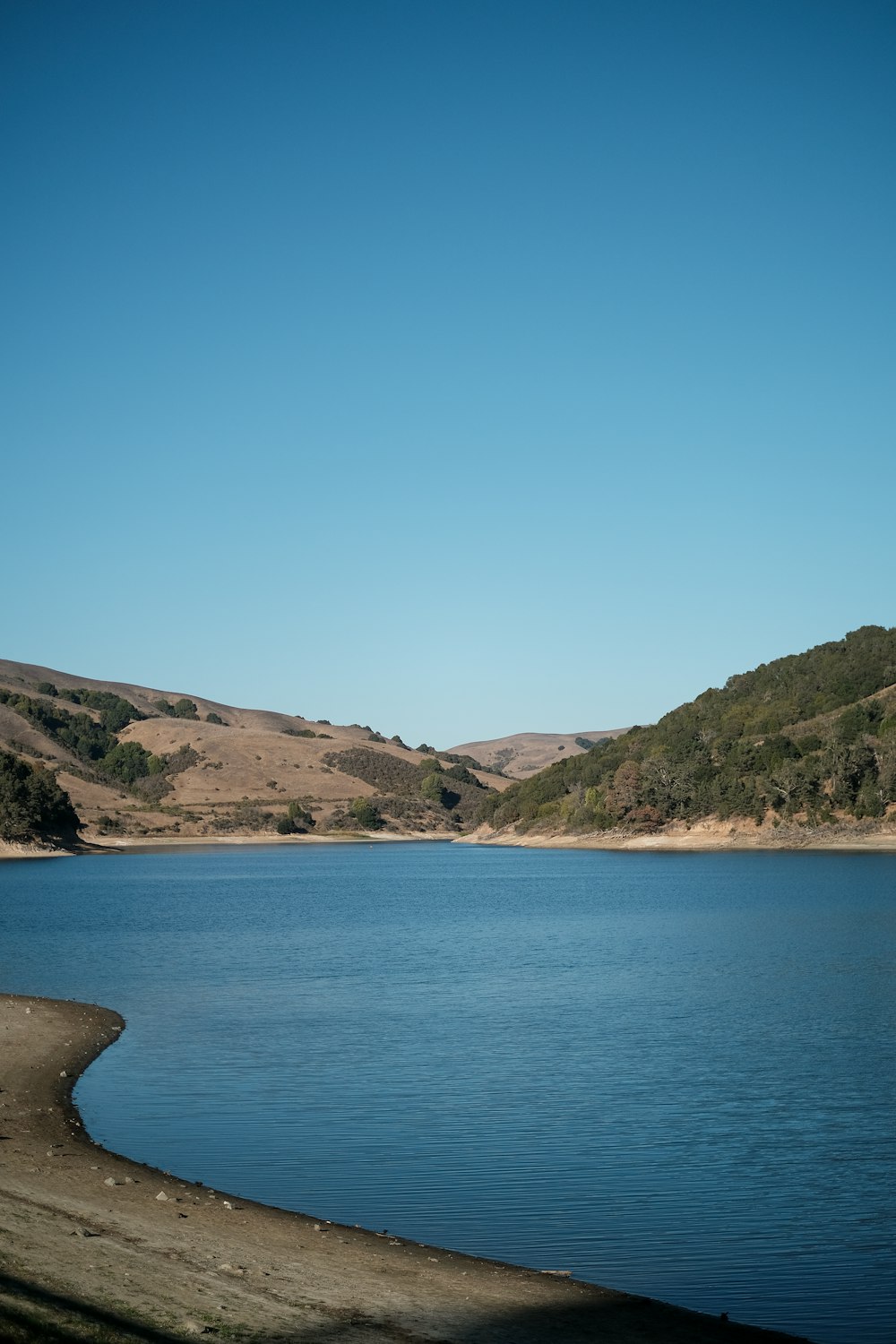 blue sea near green mountain under blue sky during daytime