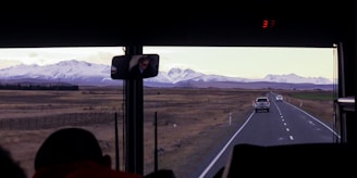 A scenic view of a bus on a highway surrounded by mountains.