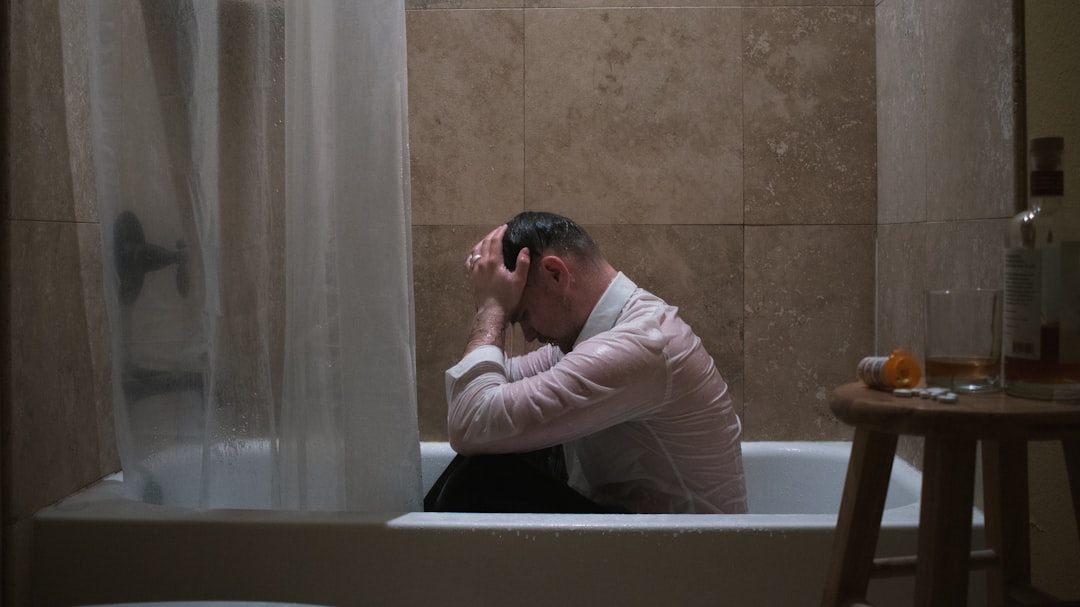 man in white long sleeve shirt sitting on bathtub