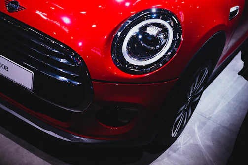 Close-up of a shiny red convertible’s front grille and headlights gleaming in the sun.