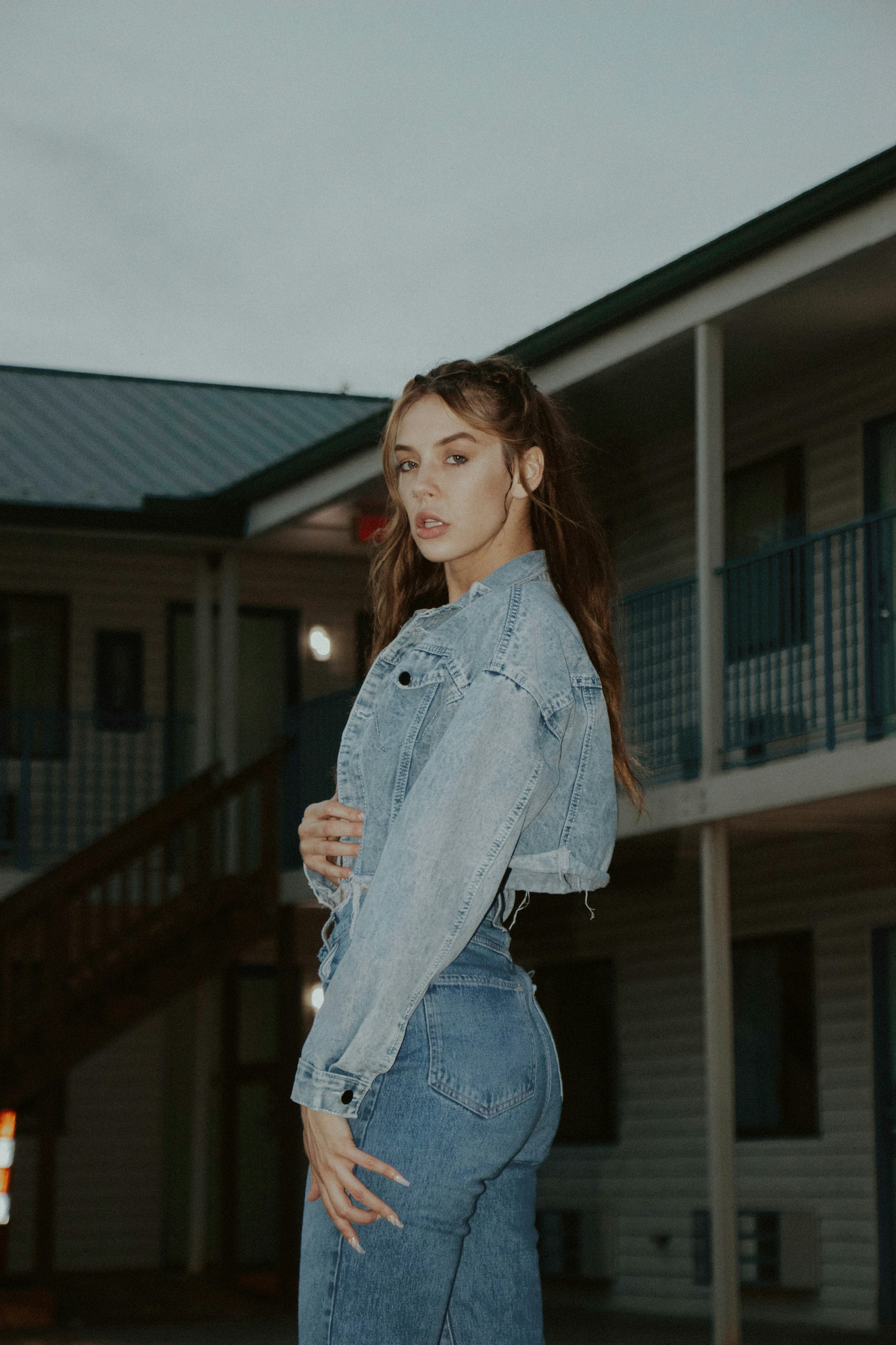 woman in blue denim jacket standing near brown wooden fence during daytime