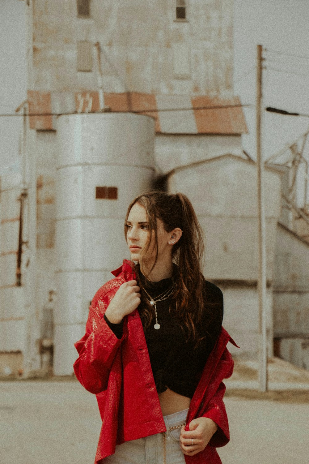 woman in red coat standing near white concrete wall