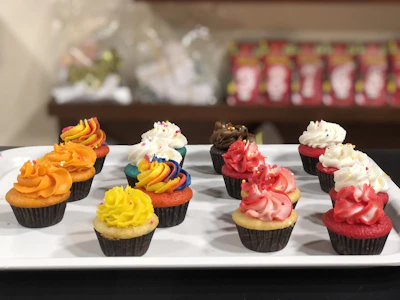 Assorted colorful cupcakes topped with creative frosting swirls and sprinkles arranged on a rustic tray.