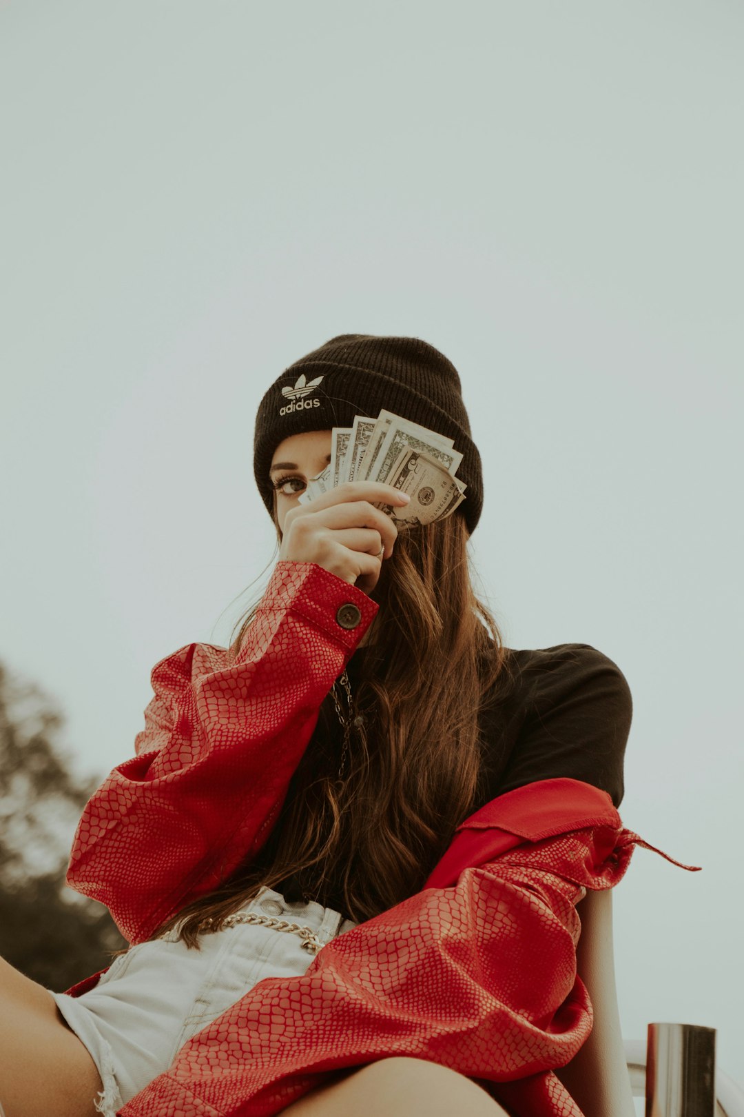 woman in black knit cap covering her face with her hand