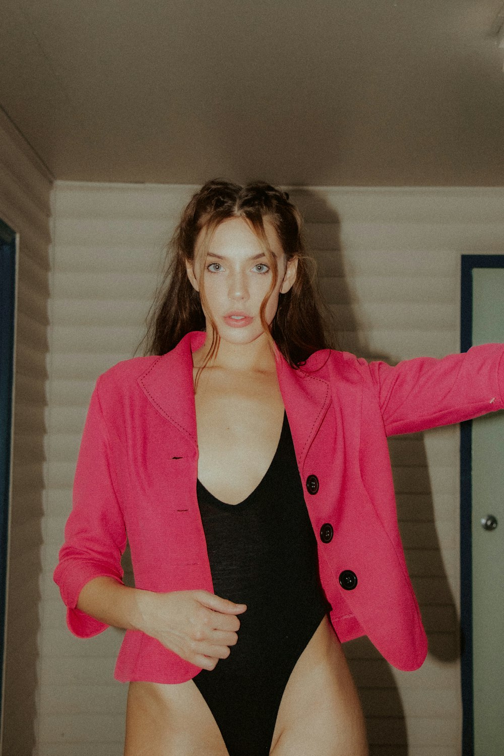 woman in red blazer standing near white wall