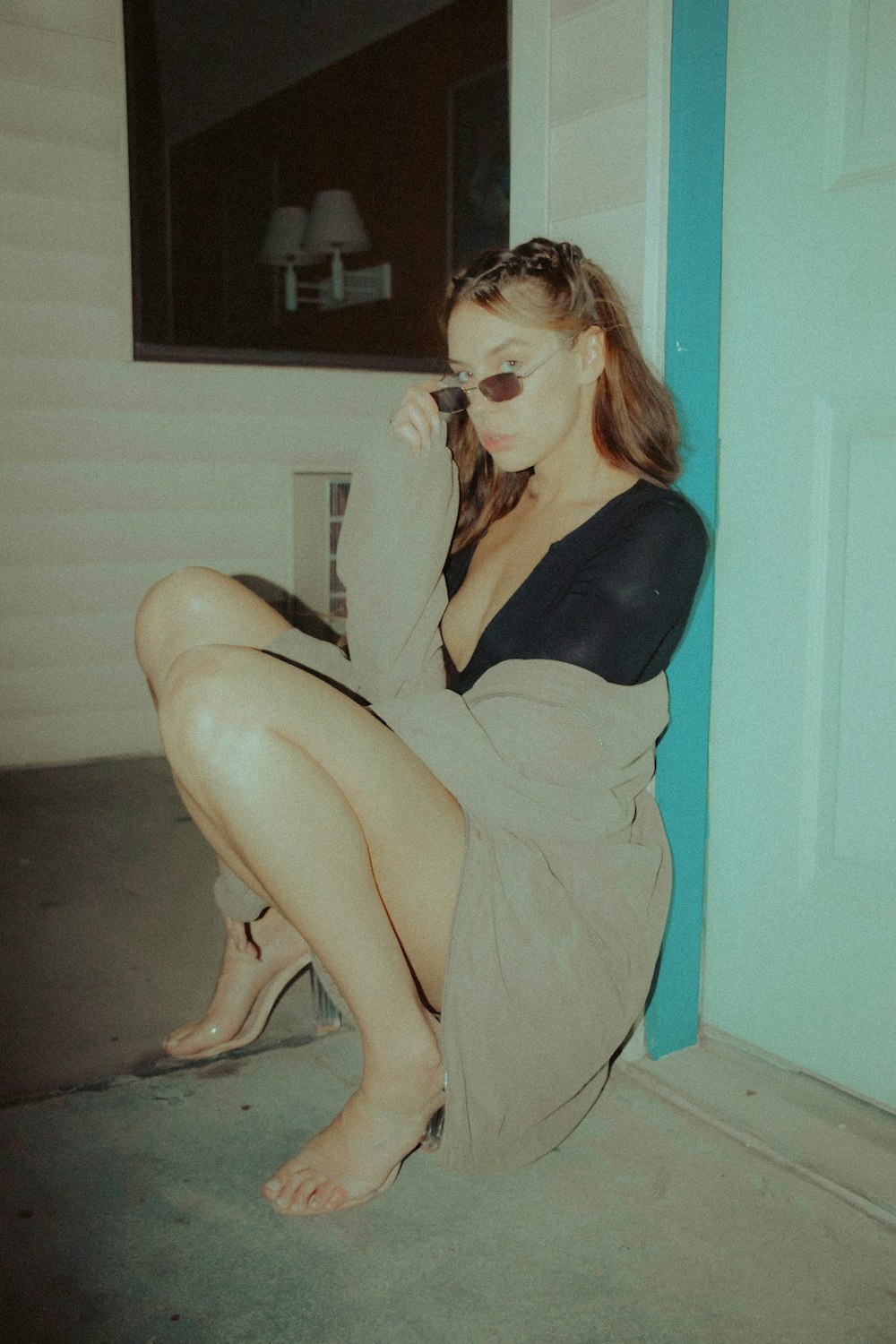 woman in black tank top and gray pants sitting on white wooden door