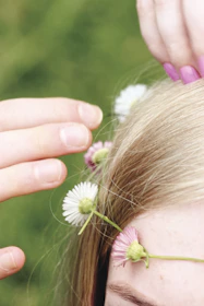 Close-up of hands weaving a flower crown with wild herbs and blossoms during a spring festival.