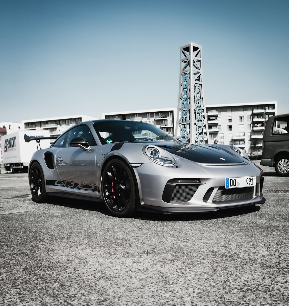 Porsche 911 azul y blanco aparcado sobre pavimento de hormigón gris durante el día