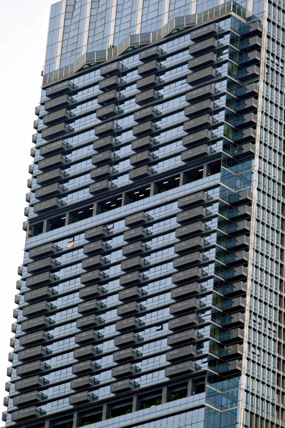 Tall, modern building with numerous glass and steel balconies visible from a low angle