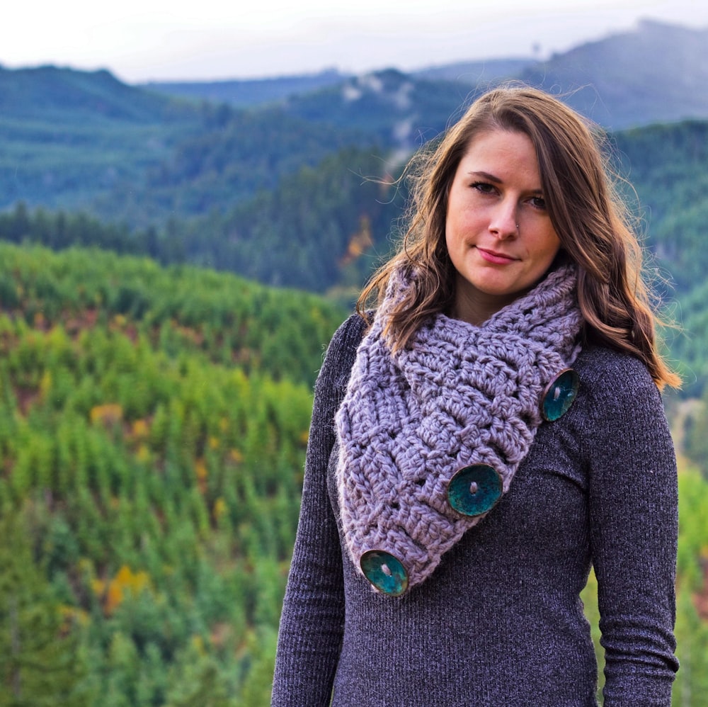 woman in gray cardigan standing on green grass field during daytime