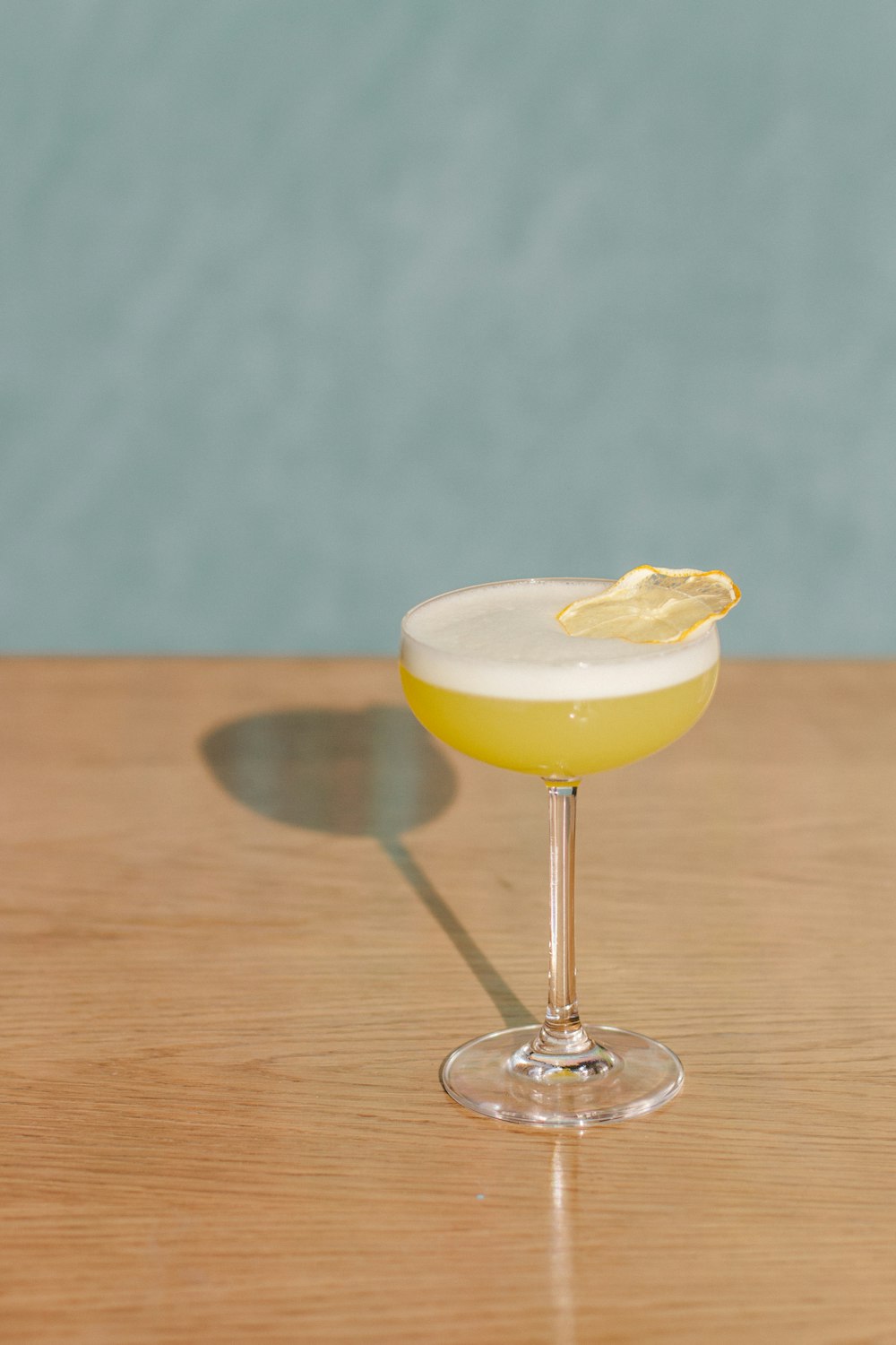 clear wine glass with yellow liquid on brown wooden table