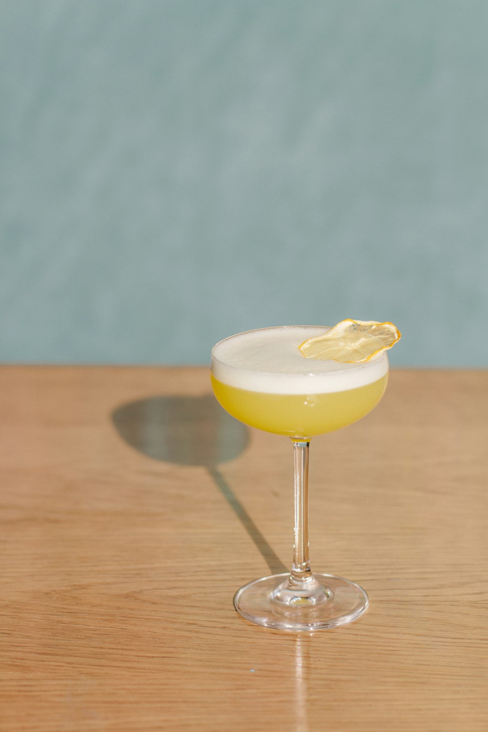 clear wine glass with yellow liquid on brown wooden table