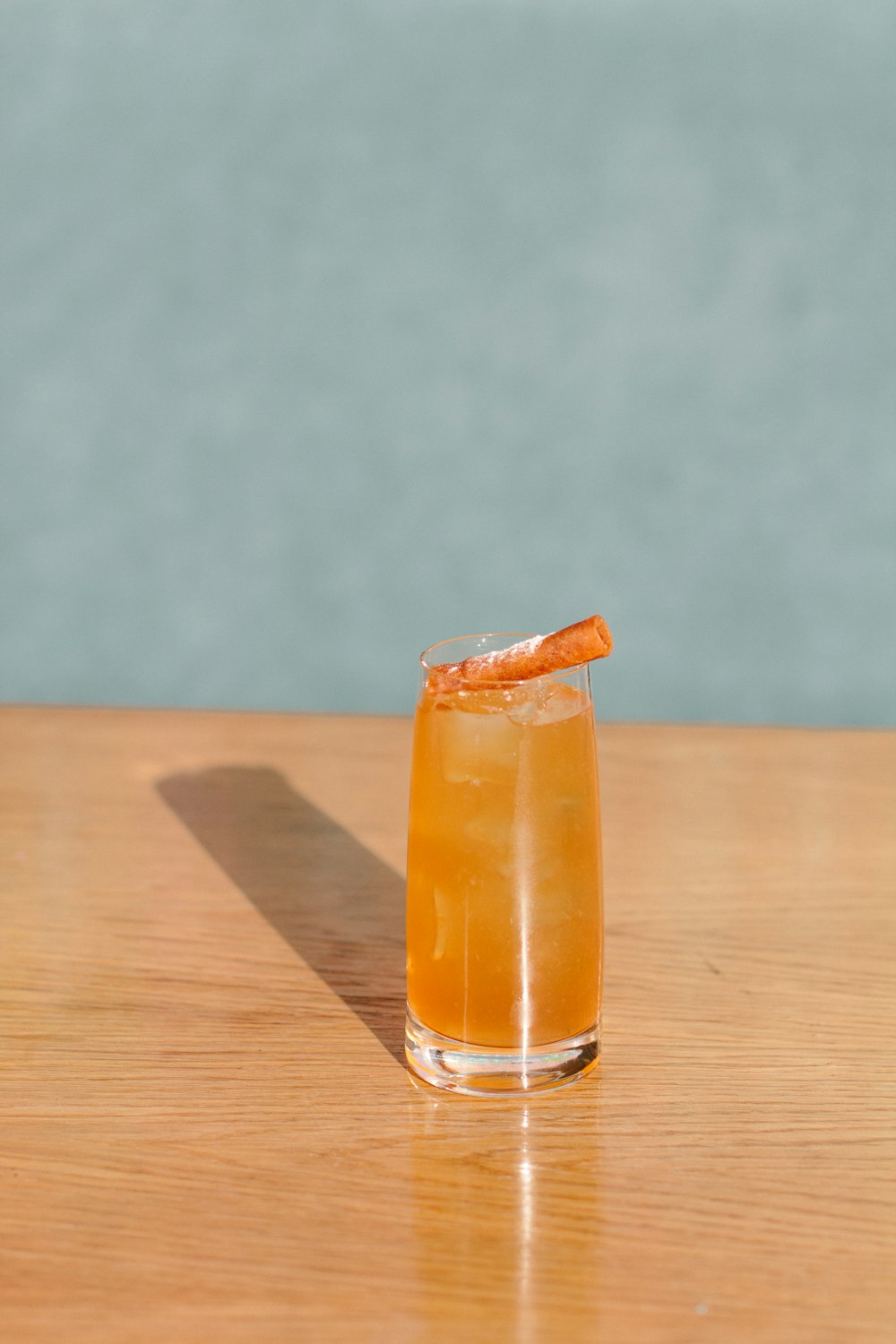 Bicchiere trasparente con liquido arancione su tavolo di legno marrone