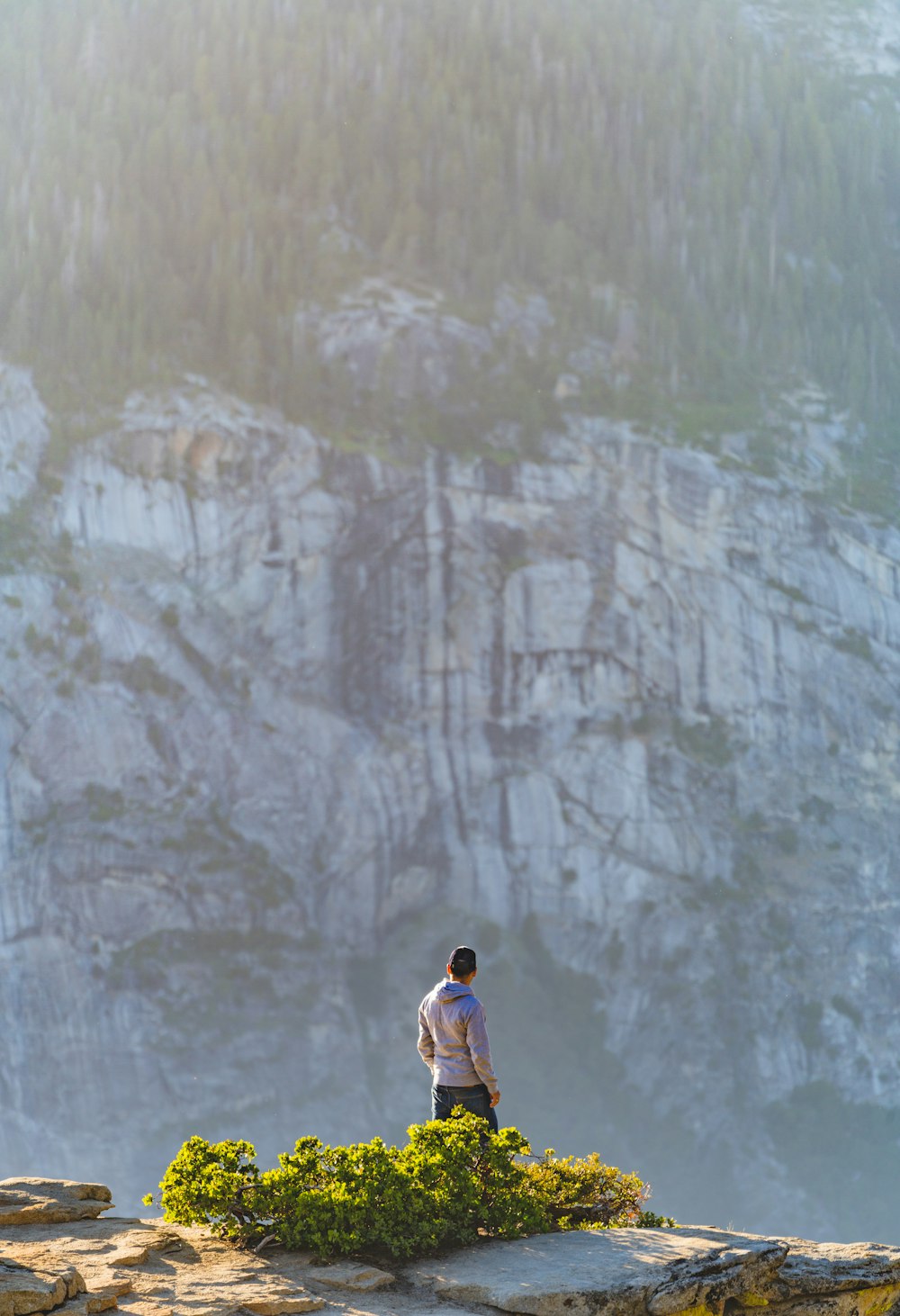 Hombre con camisa blanca de pie en la montaña de roca gris durante el día