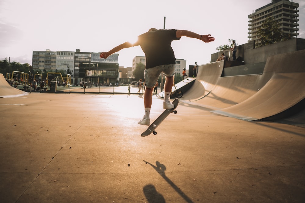 man in black t-shirt and blue denim shorts jumping on air during daytime