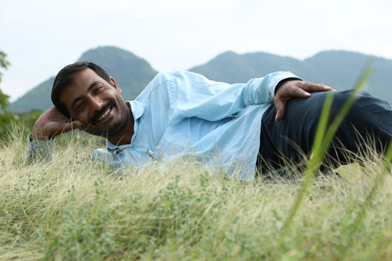 relaxed sugar daddy in a blue shirt lying on green grass