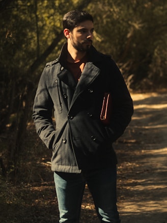 man in black jacket standing on dirt road during daytime