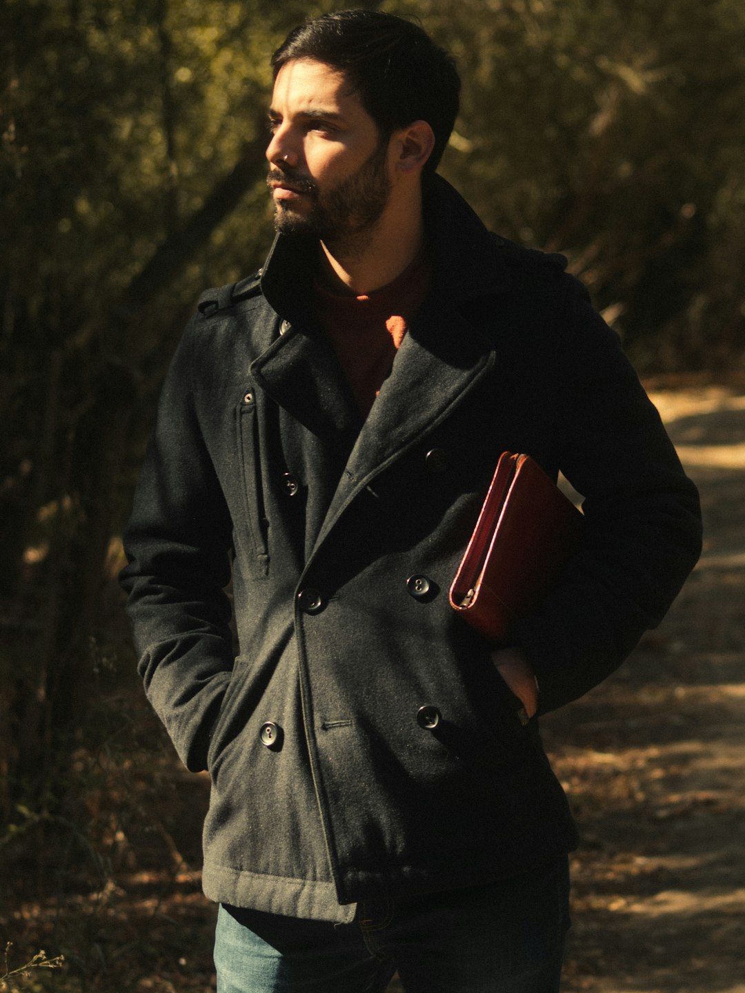 man in black coat holding red ceramic mug