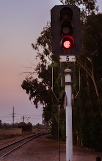 Nighttime photo of railway signals glowing red and green along a curved track.