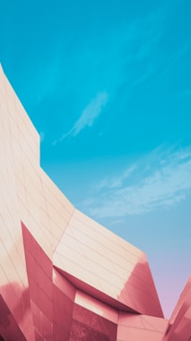 A modern architectural structure with sharp angles and reflective surfaces, under a clear blue sky.