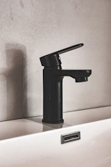 A sleek, matte black faucet installation gleaming under soft lighting in a modern upscale bathroom.