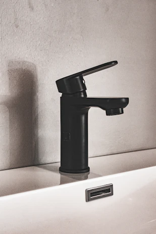A professional plumber installing a sleek faucet in a modern bathroom setting