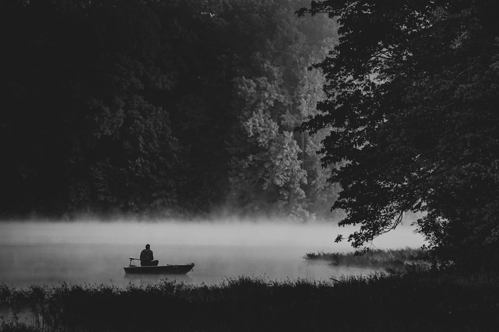 silhouette of man riding boat on lake surrounded by trees