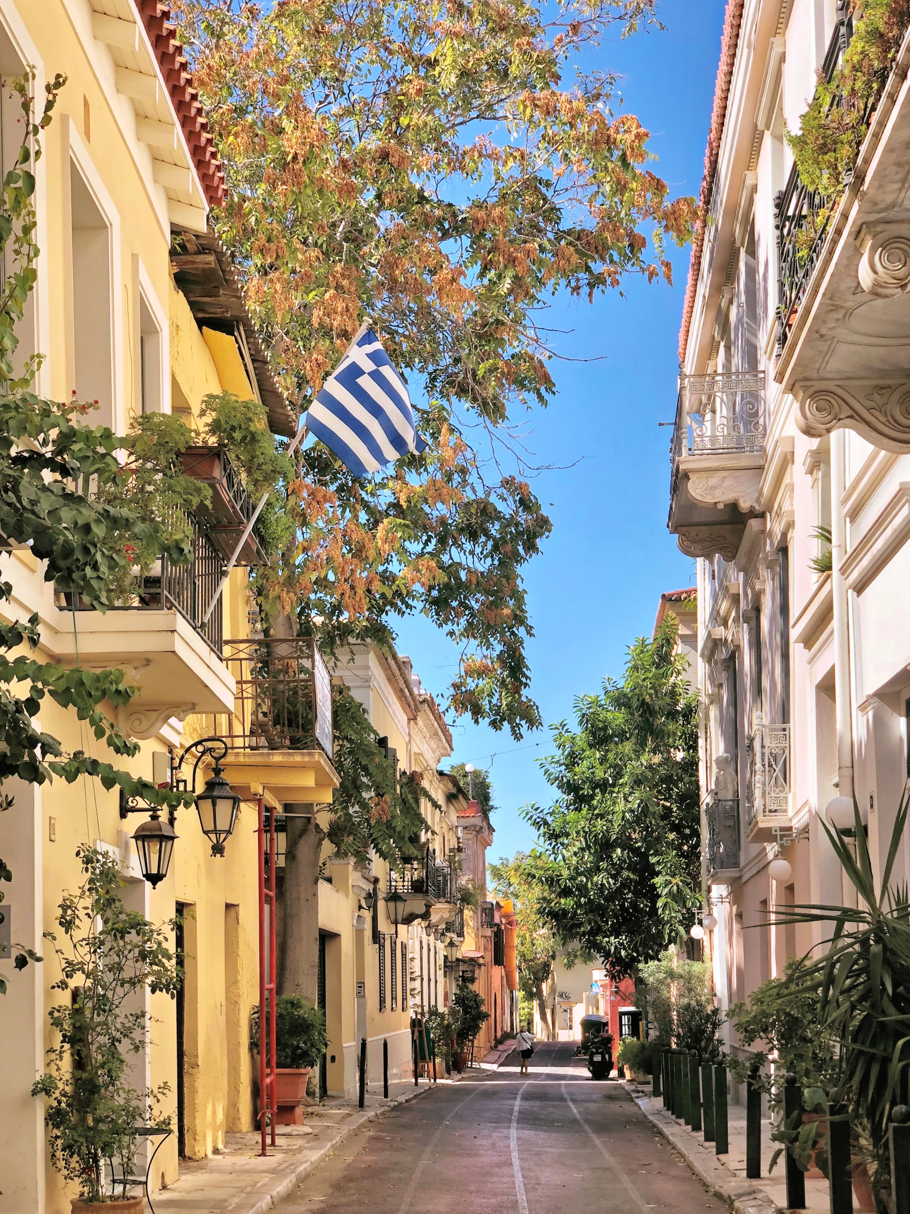 A quiet street below the Acropolis, a flag over the balconies.