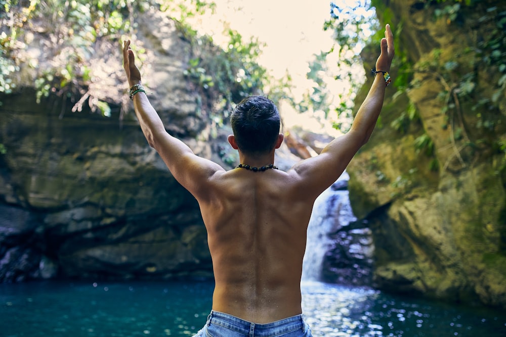 man in blue denim shorts standing near body of water during daytime