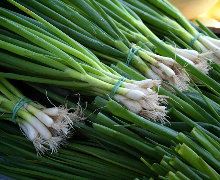 A green and white leek on a brown wooden table